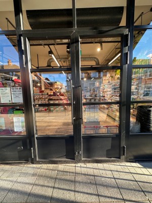 Glass doors with black, metal frames. Pull black handles in middle to open.