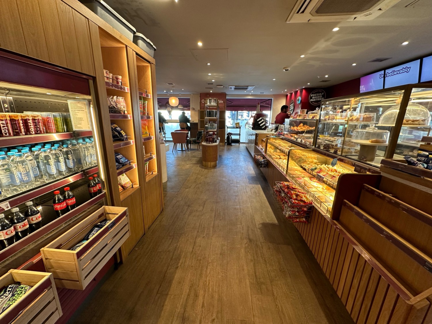 From end of path facing right. Start of counter on right. Drinks fridge on left, product shelves behind.