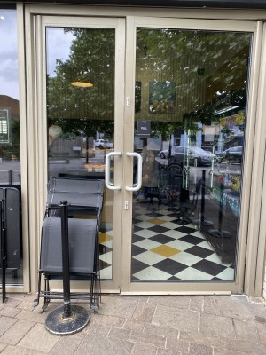 Glass doors with metal frames ahead. Pull from handles in centre to open.