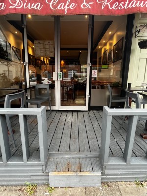 Opening ahead, followed by path leading to glass doors with white frame. Pull handles in centre to open.
