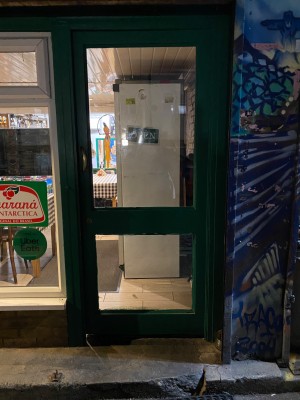 Glass door with green frame. Push from left to open.