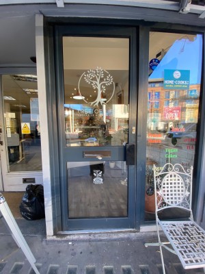 Glass door with black frame ahead. Push black metal handle from right to open. Step up at foot of door.