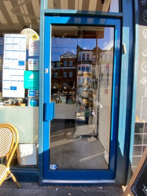 Glass door with bright blue frame. Push from left to open.