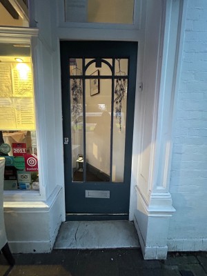 Glass door with dark blue wooden frame. Push from left to open.