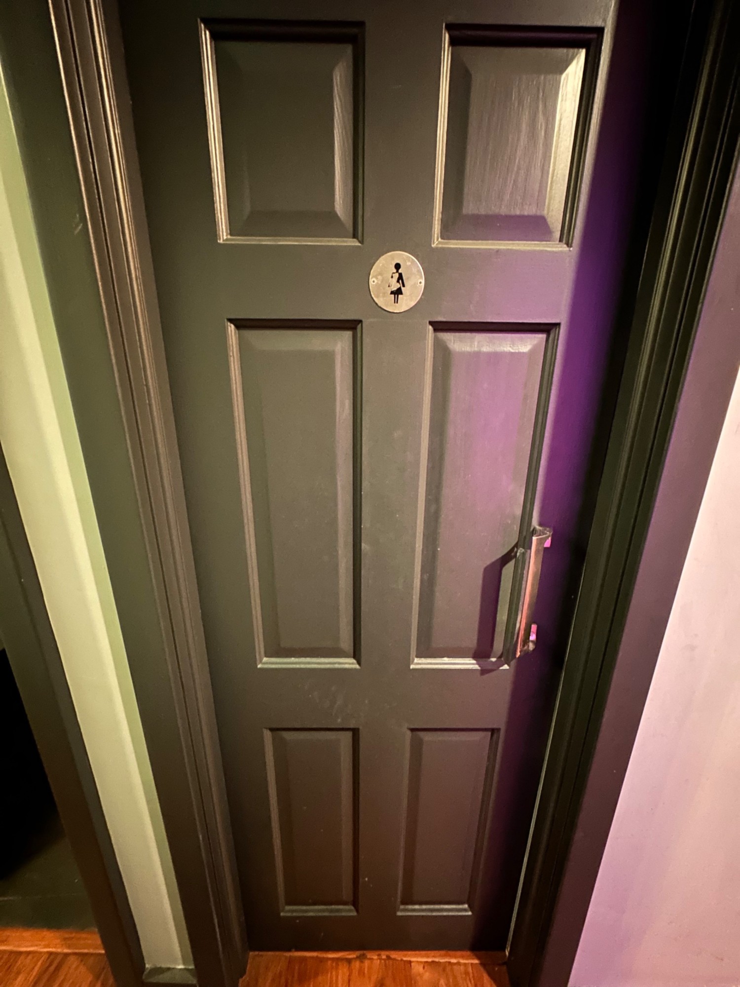 From pathway facing right. Grey wooden door ahead. Push from handle on right to open.