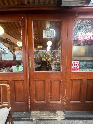 Brown wooden and glass door ahead. Push gold metal handle on left to open.