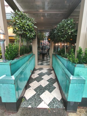 From street, facing venue. Planters along both sides. Doorway at back.