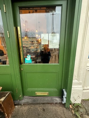 Green door with glass panel. Push from metal handle on left to open.