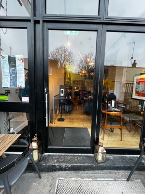 Glass door with black frame. Push from left to open.