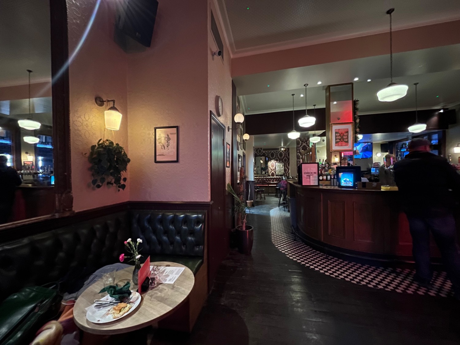 From half-booths and stools, facing right. Path ahead to to more seating. Bar counter at back right.