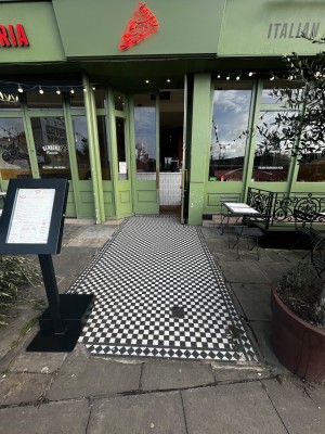 Built in ramp through outdoor street area leading to door ahead.