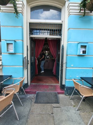 Ramp up to green framed glass doors after gates. Push from centre open. Curtains sliding from centre doors.