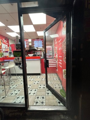 Glass door with black frame. Push from black handle on left to open.