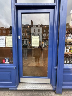 Glass door with blue frame ahead. Push from left to open.