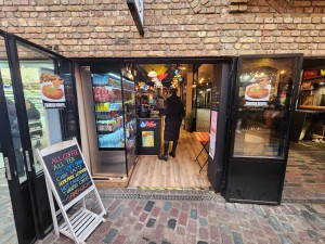 Black framed glass doors. Pull from centre to open. A-frame sign on left.