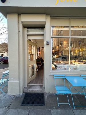 Entrance at the left of the cafe. Glass paneled door with white door frame. Push from right to open