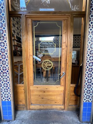 Glass door with brown, wooden frame ahead. Push silver handle on right to open.