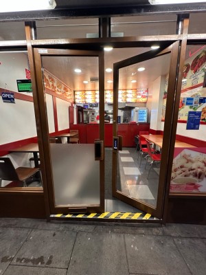 Glass doors with brown frame. Push handle in centre to open.