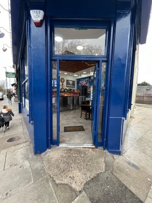 Built in ramp leading to glass door with dark blue metal frame. Push from left to open.