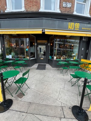 From pavement facing venue. Outdoor seatings on left and right. Path in centre to door.