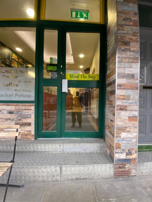 Glass door with green frame. Push from left to open.