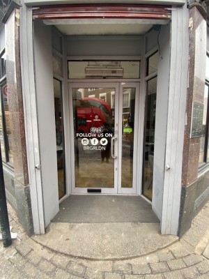 Preceding archway, then glass door with grey frame. Pull from right to open.