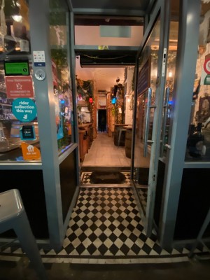 Archway, then glass door with blue frame. Pull from left to open.