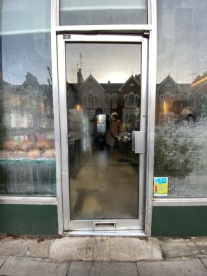 Glass door with grey frame. Push from right to open.