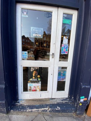 Glass door with white frame ahead. Push from metal handle on right to open.