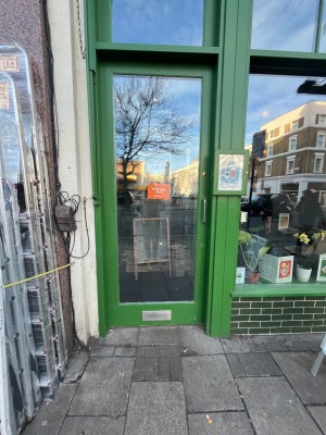 Glass door with green wooden frame. Push from right to open.