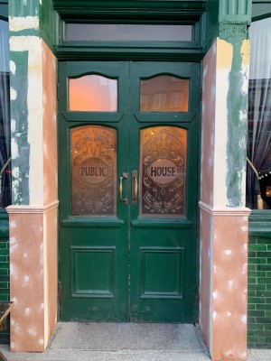 Green wooden double doors with glass panels. Pull from middle to open.
