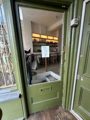 Glass door with green wooden frame. Push from right to open.