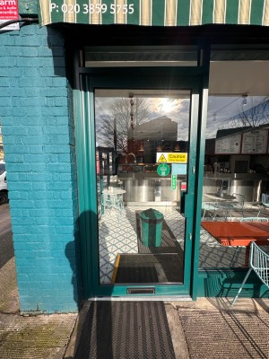 Glass door with turquoise metal frame. Push from right to open.