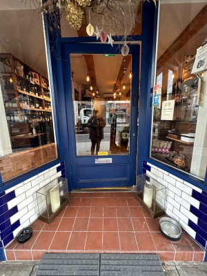 Ramp before blue and glass panelled door. Push from right to open.