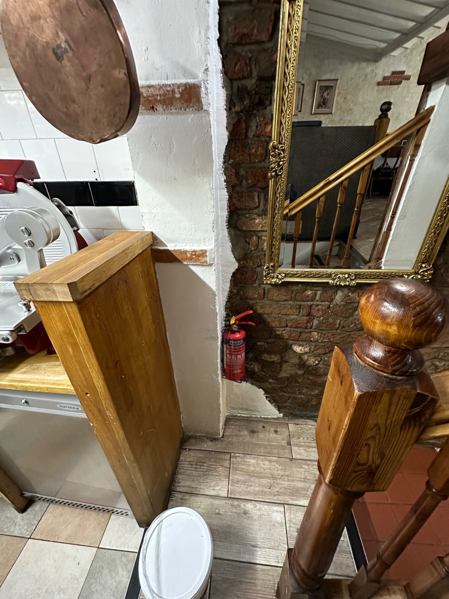 From landing looking right from bottom of first flight of stairs. Bannister on right. Kitchen on left.
