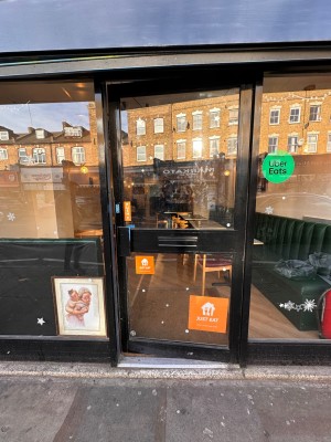 Glass door with black metal frame. Push black metal handle from left to open.