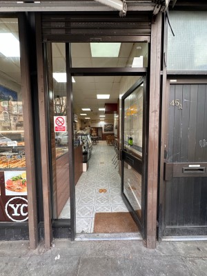 Glass door with black metal frame. Push handle on left to open.