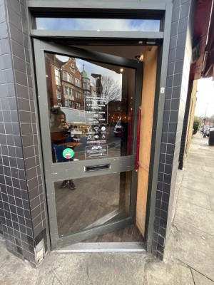 Glass door with grey frame. Push handle on right to open.