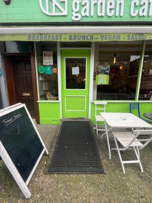 Green door with glass panel and white frame ahead. Push from right to open.