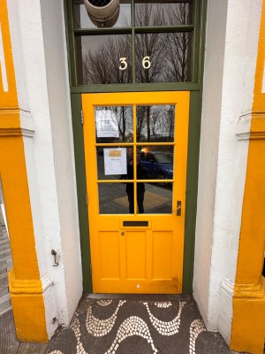 Glass door with yellow frame. Push handle on right to open.