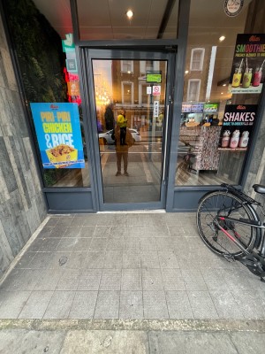 Glass door with grey frame. Push from right to open.
