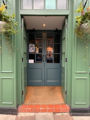 Green double wooden and glass doors ahead. Push from centre to open. Second green wooden and glass doors following. Pull from centre to open.