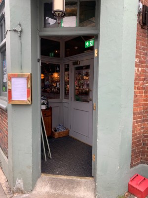Grey wooden door ahead. Push from handle on left to open.