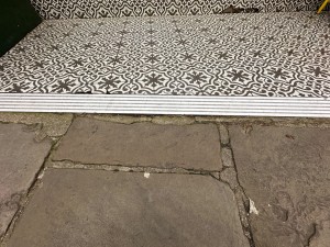 Small metal ramp from concrete street floor to tiled area before main entrance.