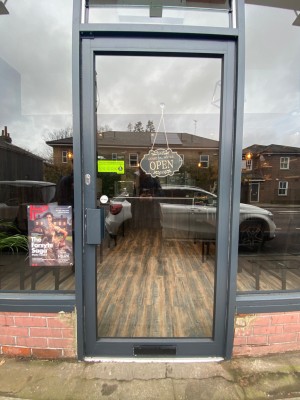 Glass door with grey frame. Push grey handle on left to open.
