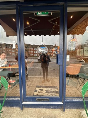 Glass door with blue wooden frame ahead. Push from right to open.