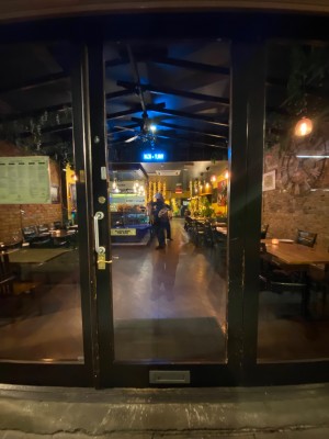 Glass door with black frame. Handle on left. Push to open.