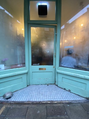 Glass door with light blue frame. Push golden handle on right to open.