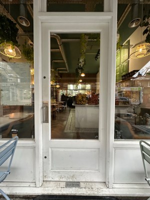 Glass and wood panelled door with white frame. Push from left.