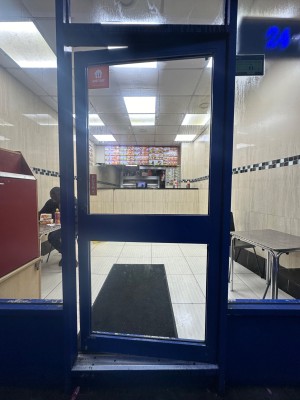 Glass door with blue, metal frame ahead. Push from left to open.